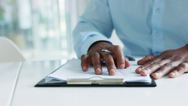 Businessman, interview and working on form looking over a contract, applying for a job or collecting information. African male worker checking document or chart for errors, corrections or amendments.