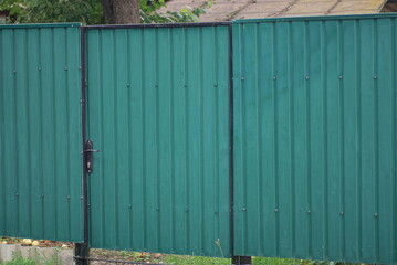 one iron closed door and green metal fence wall on a rural street