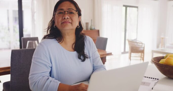 Mature woman doing remote work while planning ideas, budget and browsing research online on a laptop from home. Portrait of a happy, smiling and cheerful latino lady busy as a freelance entrepreneur