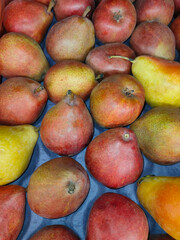 large red and yellow pears in a box on the supermarket counter 