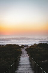 Vertical shot of a wooden bridge leading up to the Bolonia beach at sunset