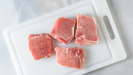 Raw pork chops close up on cutting board directly from above on marble background