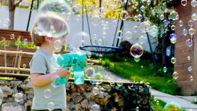 Close portrait of a cute boy play with soap bubble gun