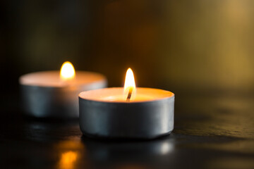Selective focus. Dark background with burning candles and golden bokeh for a special occasion