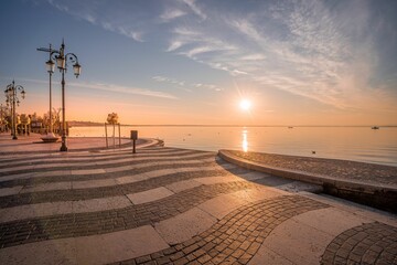Sunset shot of the embankment of Lake Garda in Lazise Italy with striped ground and sun shining