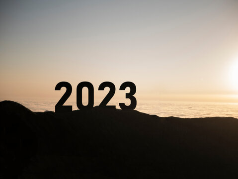number 2023 on the mountain peak, happy new year, success and freedom concept