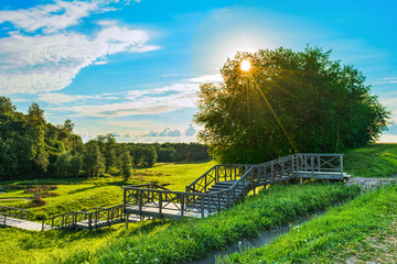 View of the multi-level wooden gangway in a picturesque place with a field and a forest. Summer evening before sundown. Nature landscape background