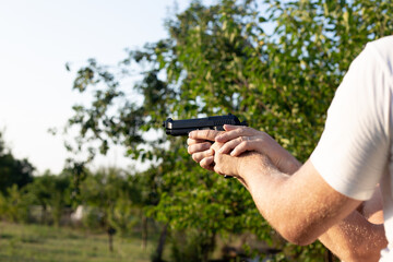 The man supports the hands of another man in which the gun. Pistol shooting training. Recreation and hobby