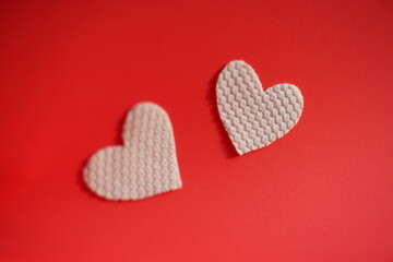 Two white fabric hearts on vivid red table. Art card. Copy space