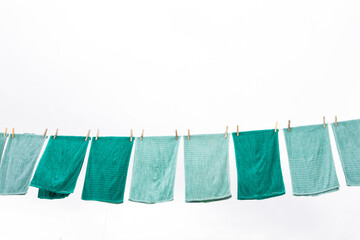Blue and green towels hanging and drying after washing, with a clean and clear sky