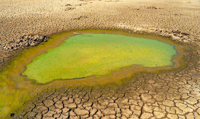 Polluted river water, oil spill, cracked soil during summer drought