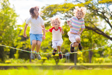 Happy kids play outdoor. Children skipping rope.