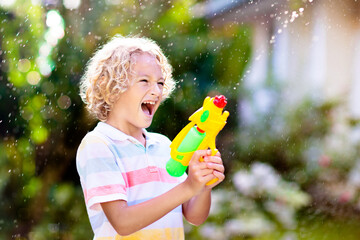 Kids with water gun toy in garden. Outdoor fun.