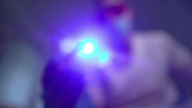 Close-up dental penlight in male hand turning on and turning off device. Unrecognizable blurred Caucasian male dentist using equipment examining oral cavity. Patient POV. Slow motion