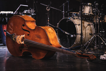 Acoustic double bass on stage with drums on background during a jazz concert.