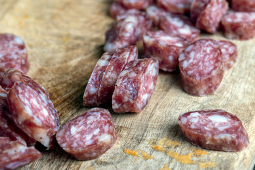 sliced thin sausage with bacon on a wooden dish