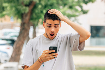 shocked young man on the street looking at mobile phone or smartphone