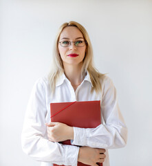 A young businesswoman with a red folder in her hands is standing in the office.