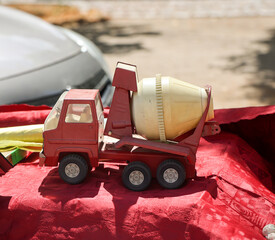 Auf einem Tisch steht ein rotes und gelbes Spielzeugauto, ein Betonmischwagen. Spielzeug für...