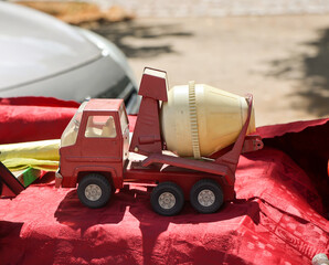 Auf einem Tisch steht ein rotes und gelbes Spielzeugauto, ein Betonmischwagen. Spielzeug für...