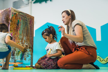 Cling film painting. Toddler painting with a sponge, brushes and paints on a cling film wrapped all...
