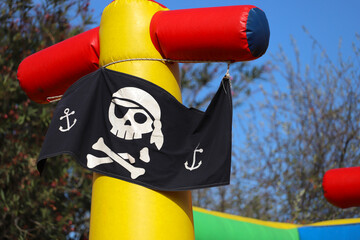 Pirate flag. Inflatable castle in the shape of a pirate ship. Outdoor game for children. Fun for...