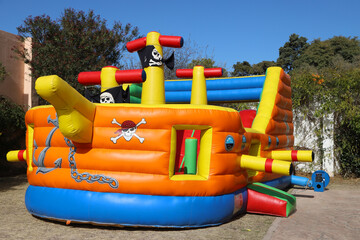 Inflatable castle in the shape of a pirate ship. Outdoor game for children. Fun for boys and girls.  Children's birthday. Fun in amusement park. Childhood. Children's party. Pirate flag.