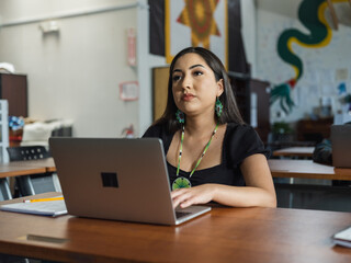 Fototapeta premium Wide angle of a Native girl student on her computer during class while looking up