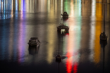 Boats at night on Sydney Harbour light by city reflections