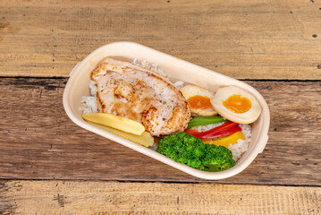 Lunch tray with a combo of boiled egg, white rice, broccoli and other vegetables and a grilled chicken fried steak