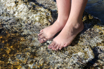 Girl's feet splashed by clear sea water