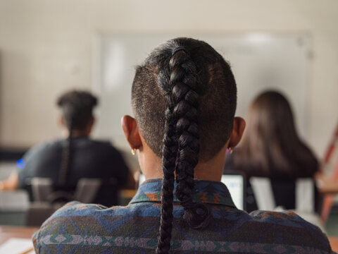 Over shoulder image of a native boy with braids in class