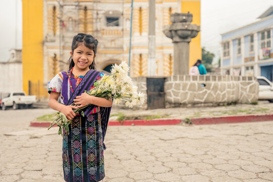 Portrait of a beautiful indigenous girl with flowers in her hands and a colorful dress from Zunil Quetzaltenango.