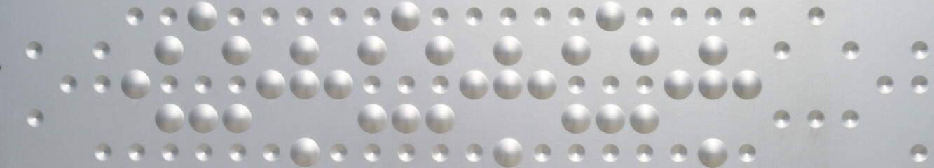 Round dents and dots in silver metal as a graphic background
