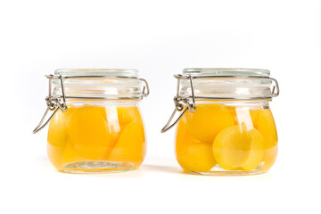 sweet canned yellow peaches in glass jar isolated on white background