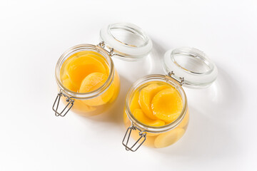 sweet canned yellow peaches in glass jar isolated on white background