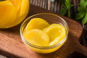sweet canned yellow peach in glass jar on table