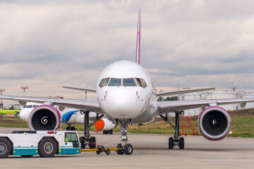 Pushback passenger jet aircraft procedure. Low-profile vehicle called pushback tractor or tug moves...