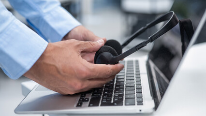 A man puts a headset on a laptop keyboard in the office.