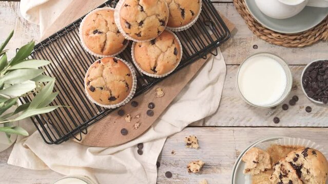Chocolate chip muffins with milk served on glass cups on white kitchen countertop.