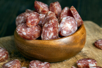 sliced thin sausage with bacon on a wooden dish