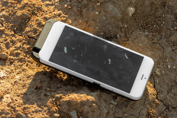 Lost white smartphone on the ground. Forgotten mobile phone on the ground