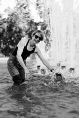 Happy woman in hot summer in city fountain.