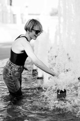 Happy woman in hot summer in city fountain.