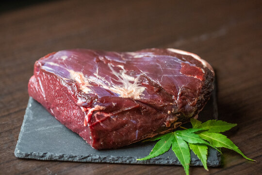 和食レストランで提供される新鮮なジビエ料理用の最高級鹿肉ブロックと彩りを添える紅葉の葉。テキストを入れるスペースあり