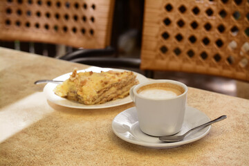 Piece of delicious cake and coffee on beige table