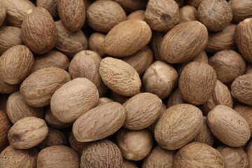 Heap of nutmeg seeds as background, closeup