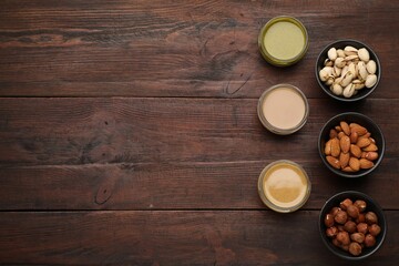 Fototapeta na wymiar Different types of delicious nut butters and ingredients on wooden table, flat lay. Space for text