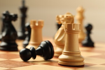 Chessboard with game pieces on beige background, closeup
