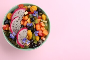 Delicious exotic fruit salad on pink background, top view. Space for text